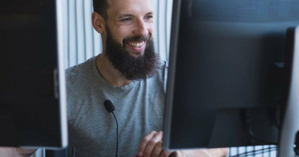 smiling tech professional between two monitors