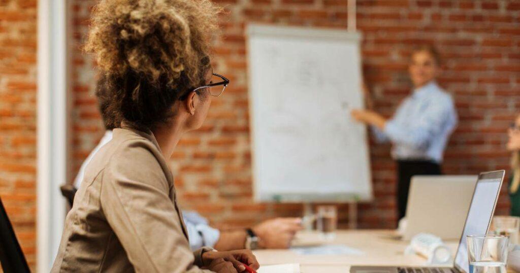 woman looking at colleague presenting during meeting