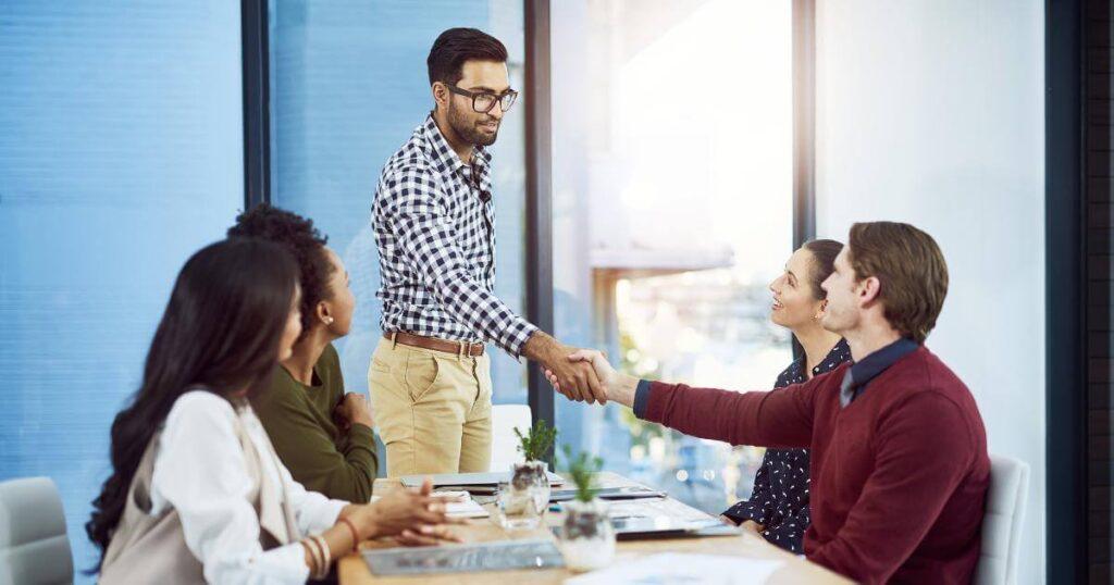 two coworkers shaking hands in team meeting