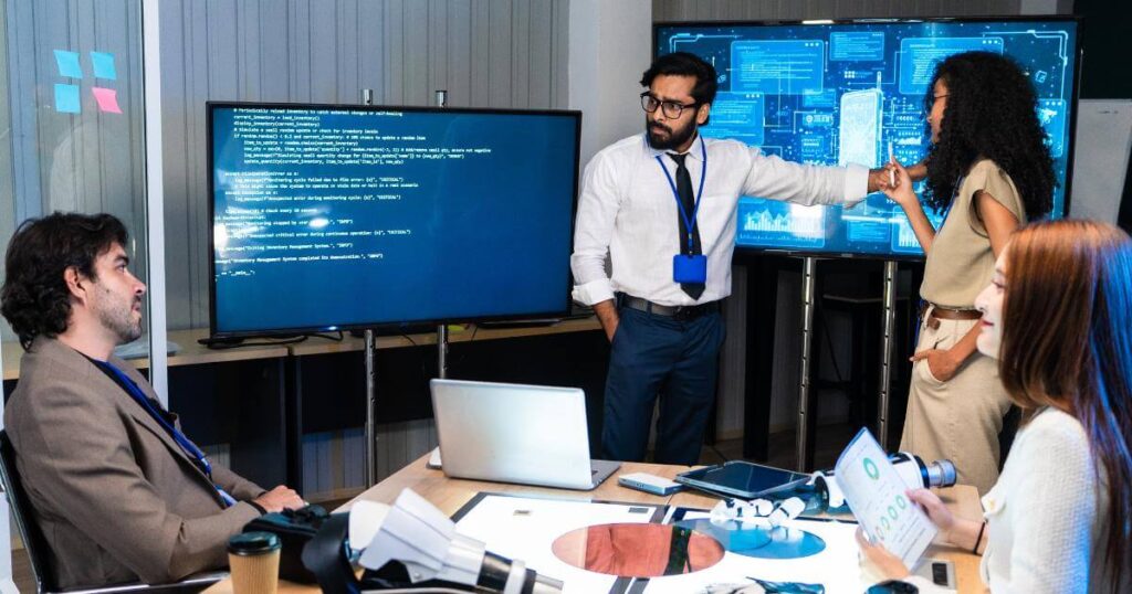 Team reviewing code and data on screens — AI meeting real system complexity