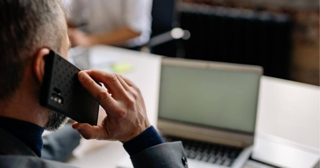 IT professional on a phone call at his desk — starting the hiring conversation before writing the job description